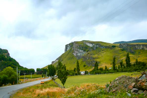 Rural road winding through farmland with green fields and farm equipment nearby