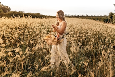 woman walking with basket of flowers at the flower field during day