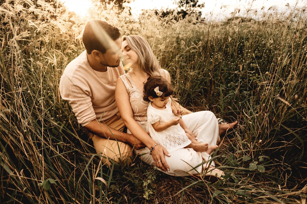 man and woman kissing with toddler on their knee