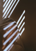 A model draped in sheer fabric, bathed in gentle champagne gold light against an obsidian black backdrop.