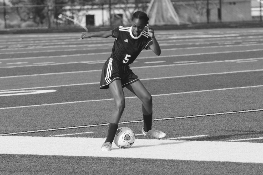 grayscale photography of woman playing soccer