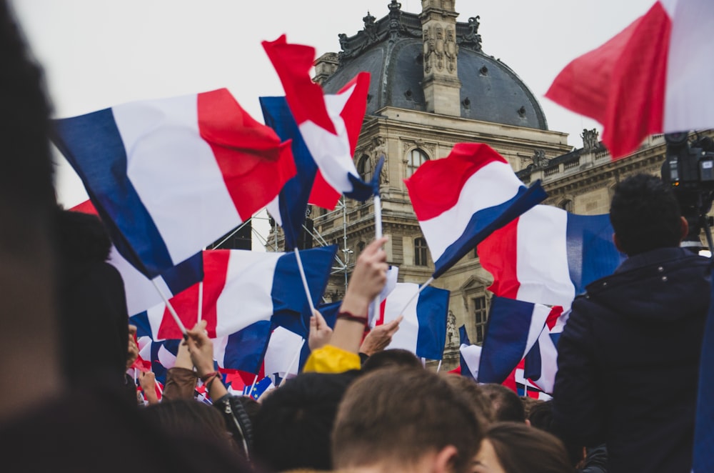 des gens qui brandissent le drapeau de la France dans la rue