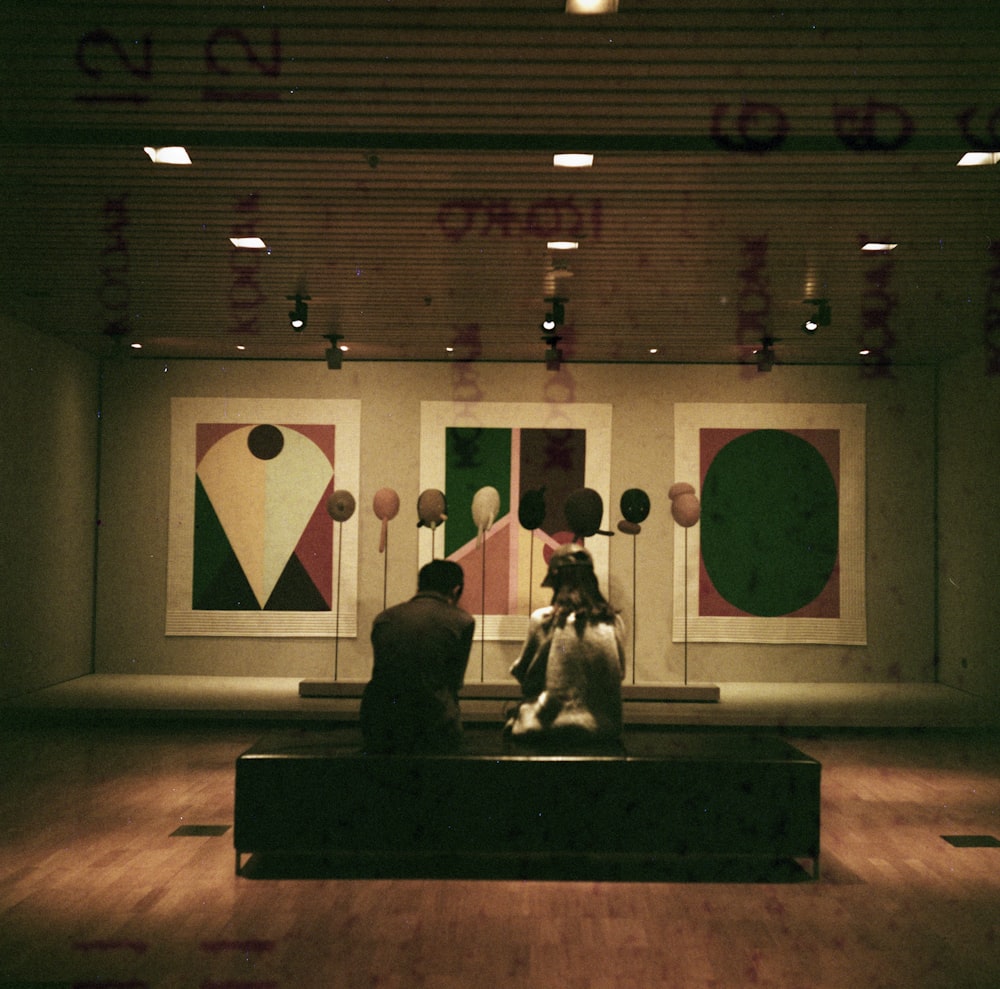 homem e mulher sentados em frente aos quadros