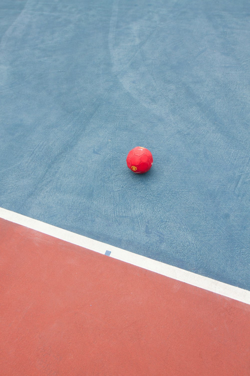 a red ball on a blue tennis court