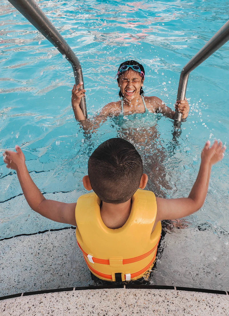 A child blowing bubbles in the pool with a beginner swim instructor