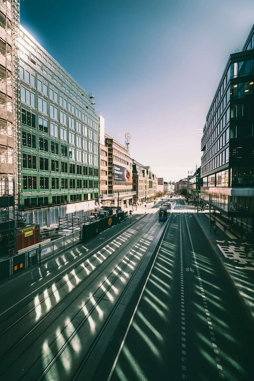 Wenige Fahrzeuge auf der Straße neben Hochhäusern unter blau-weißem Himmel