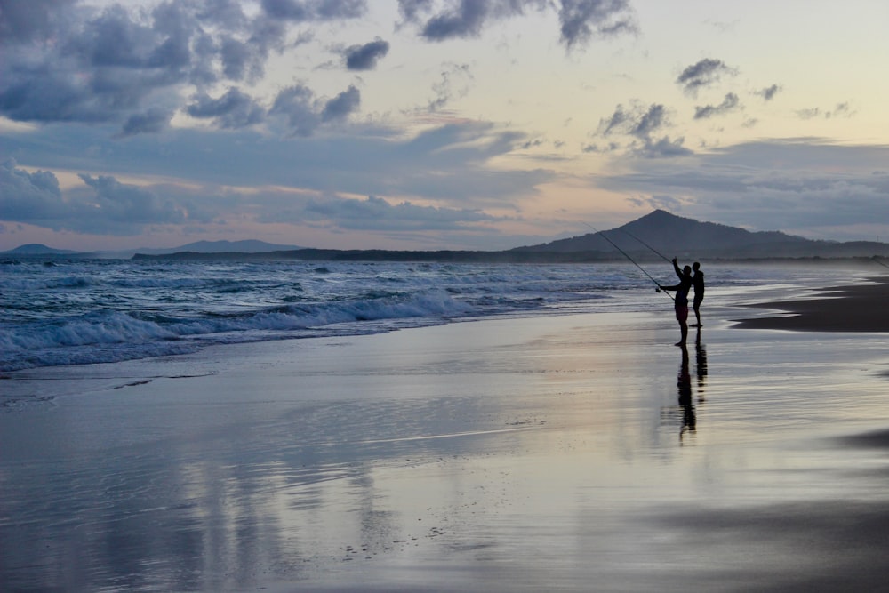 two people holding fish reels on seashore