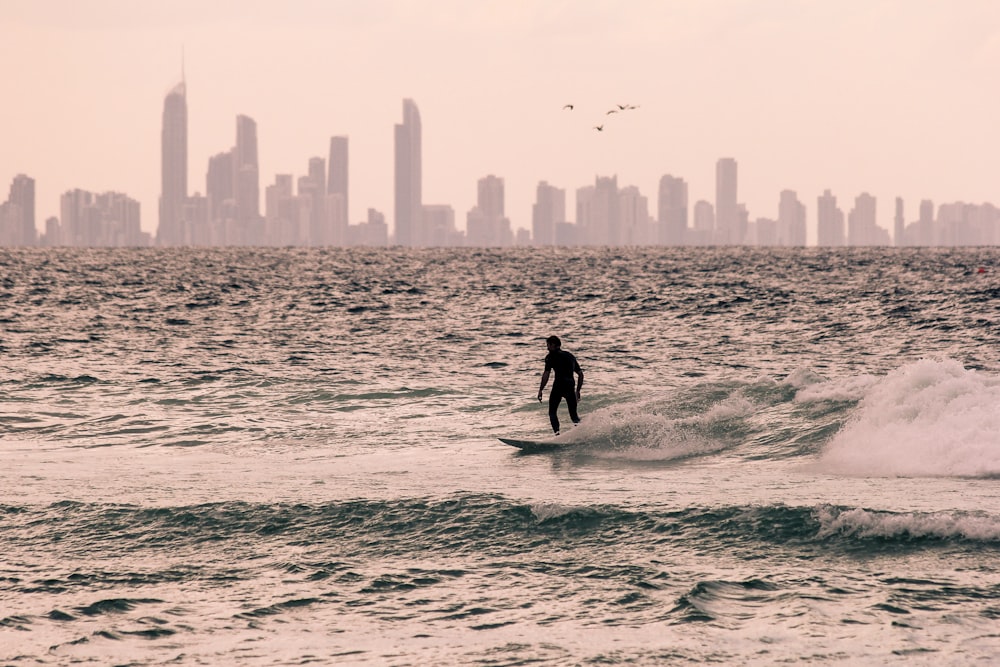 man in black wet suit surfing on sea waves during daytime