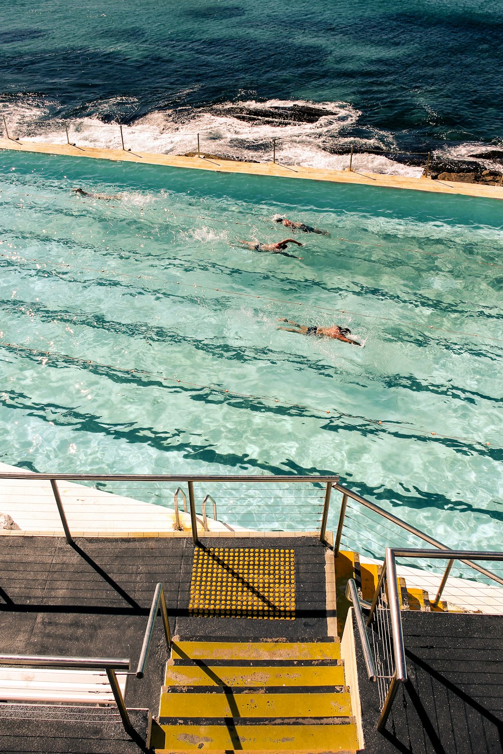 people swimming on pool beside ocean during daytime