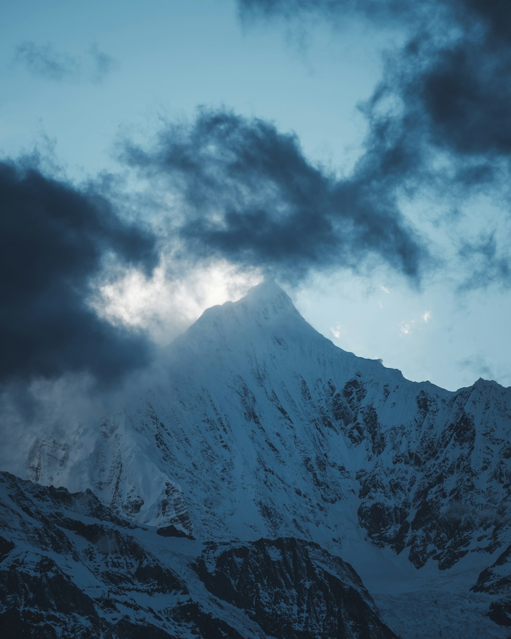 snow-covered mountain under gray clouds at daytime