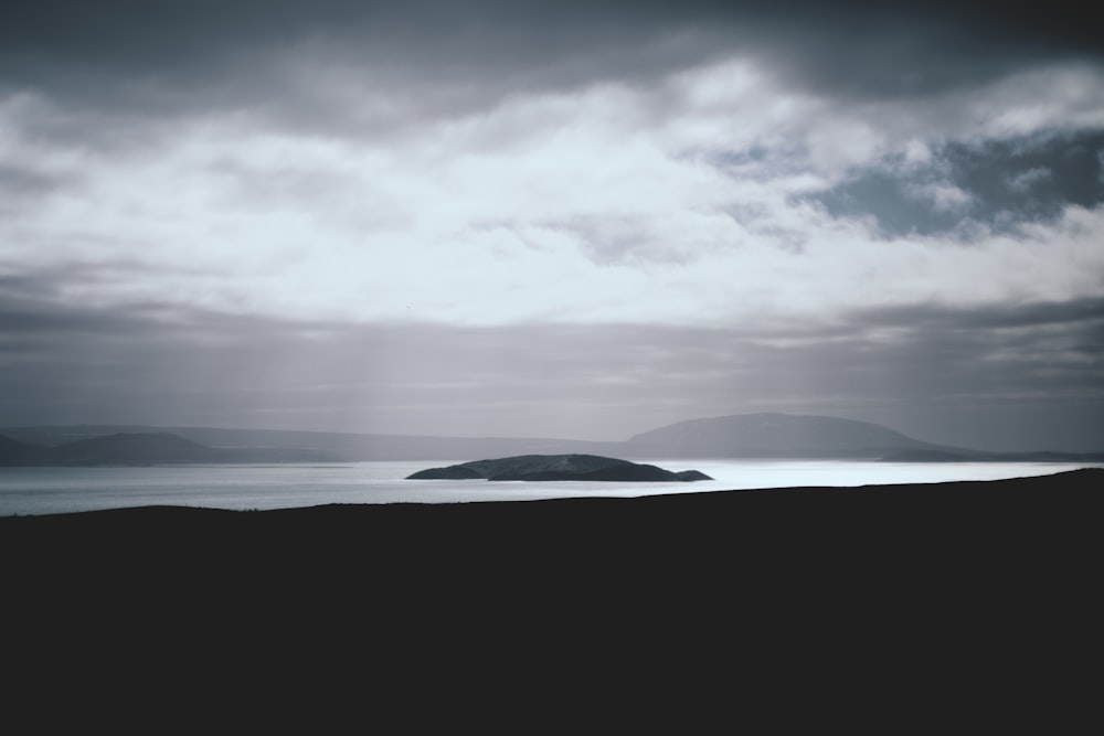 island under white clouds at daytime