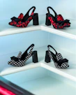 Close-up of stylish high heels arranged on a sleek modern shelf with a minimalist backdrop.