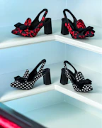 Close-up of stylish high heels arranged on a sleek modern shelf with a minimalist backdrop.