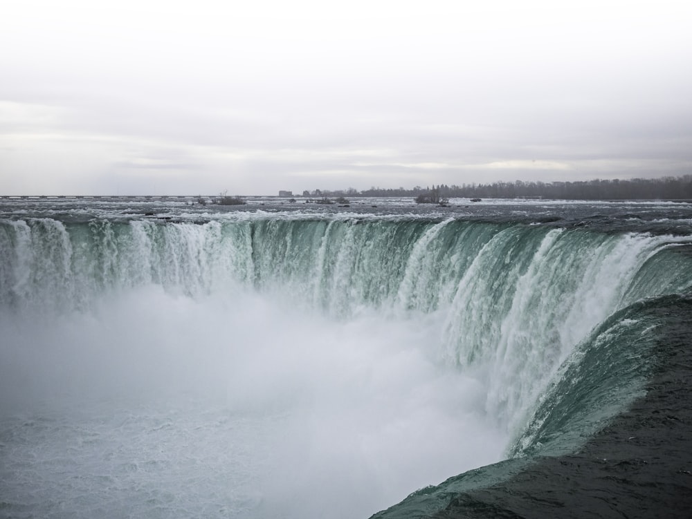 waterfall under white clouds at daytime