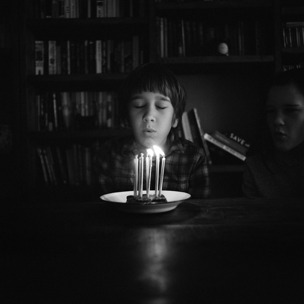 boy sitting near table and about to blow birthday candles