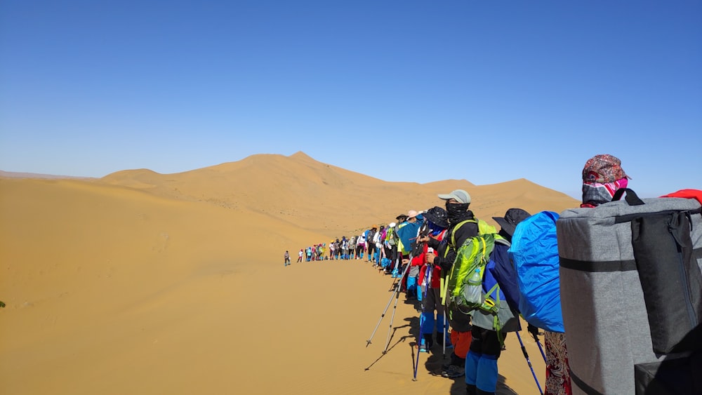 group of person on dessert area under blue sky