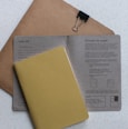 yellow softbound book on grey printer paper