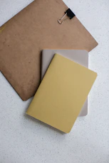 yellow and gray softbound book near brown clip board