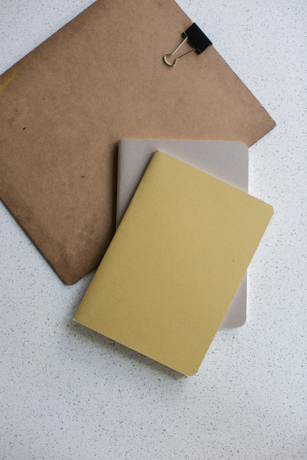 Livre relié souple jaune et gris près du presse-papiers marron