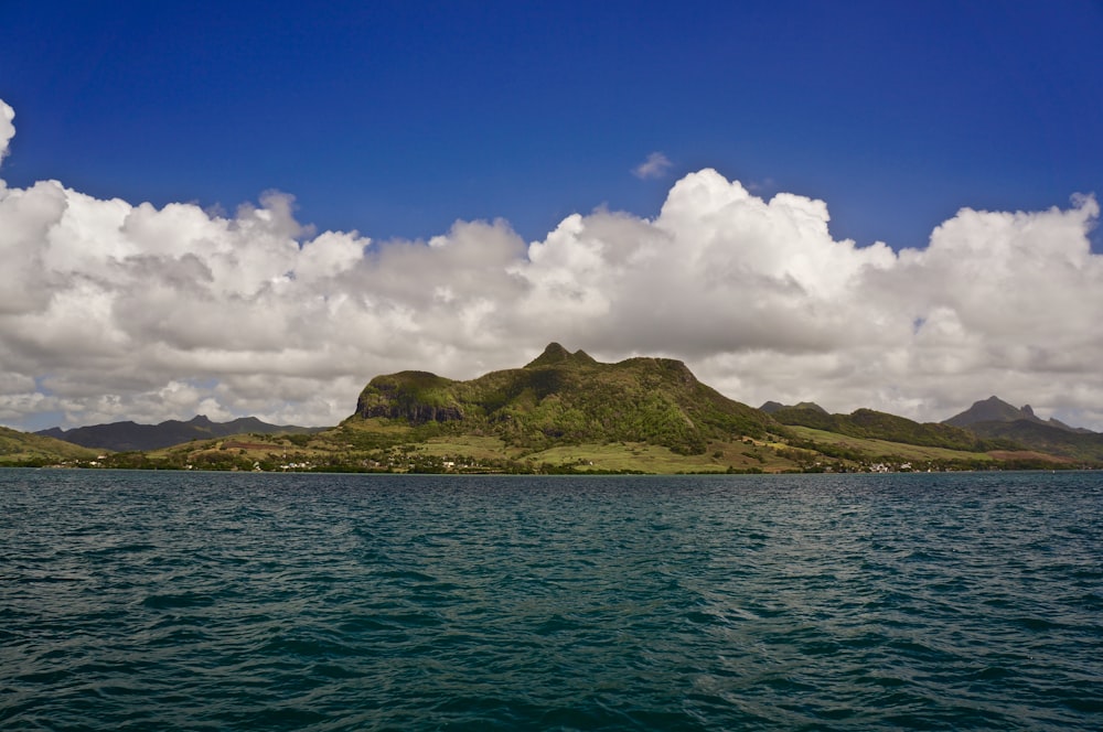 calm body of water near mountain during daytime