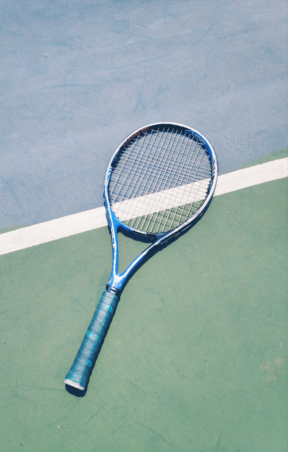 blauer Tennisschläger auf grünem Untergrund
