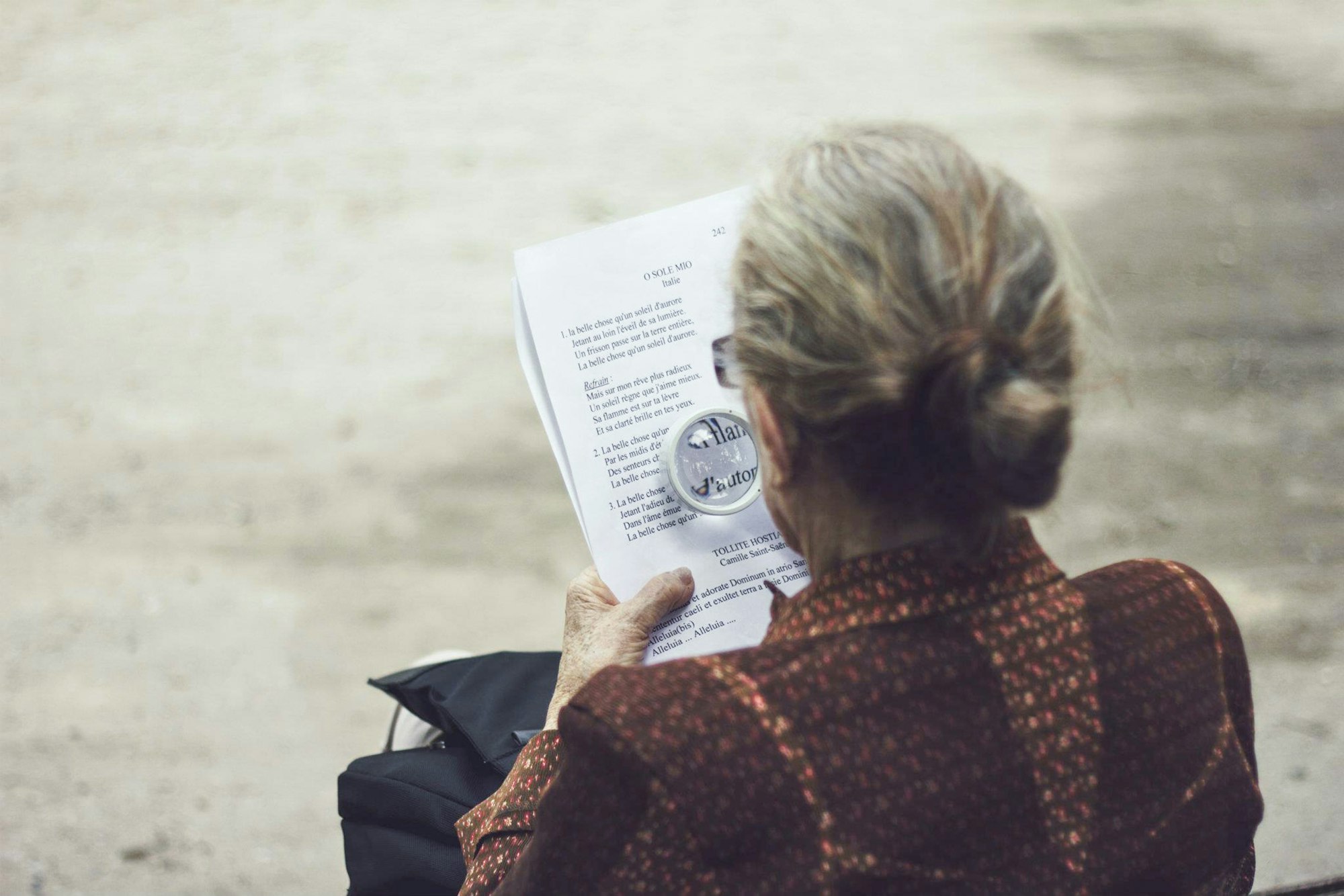 An elderly woman reading with a magnifying glass