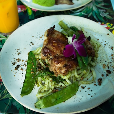A vibrant platter featuring grilled chicken, veggie pasta, and fresh Caesar salad arranged beautifully on a rustic wooden table.