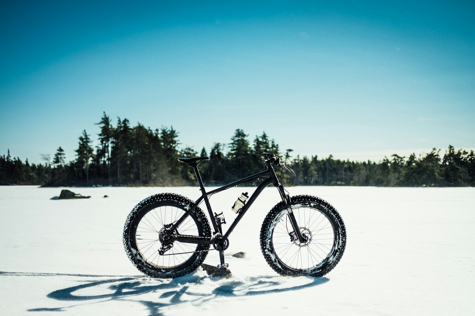 Arkistokuva: Musta fatbike-polkupyörä seisoo lumisella maalla, jossa on leveät nastapintaiset renkaat ja tukeva runko.