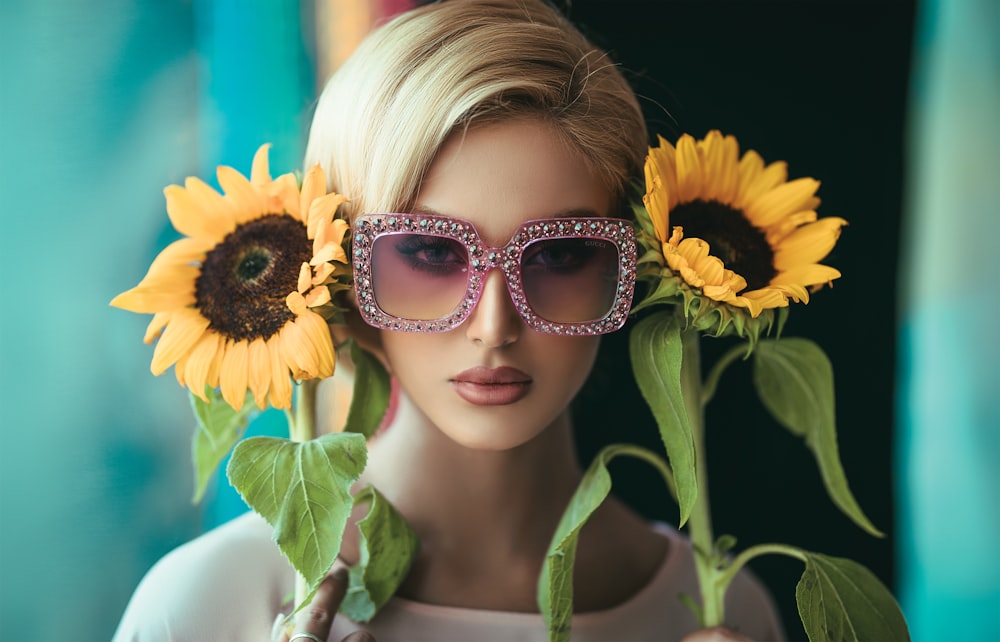 woman wearing sunglasses holding sunflowers