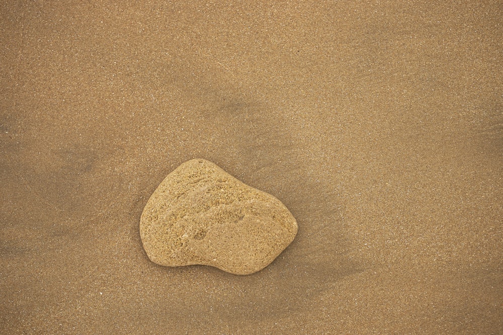 a rock sitting on top of a sandy beach