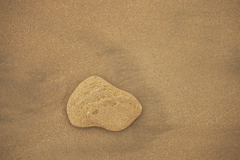 una roccia seduta sulla cima di una spiaggia sabbiosa