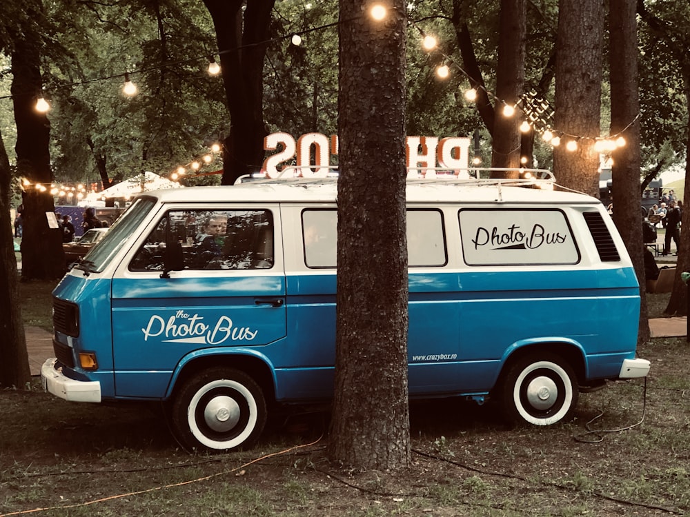 blue and white Photo Bus beside trees