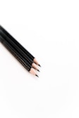 Three black pencils with sharpened tips are arranged parallel to each other on a plain white background. Each pencil has a sleek, modern design with small white polka dots along the barrel.