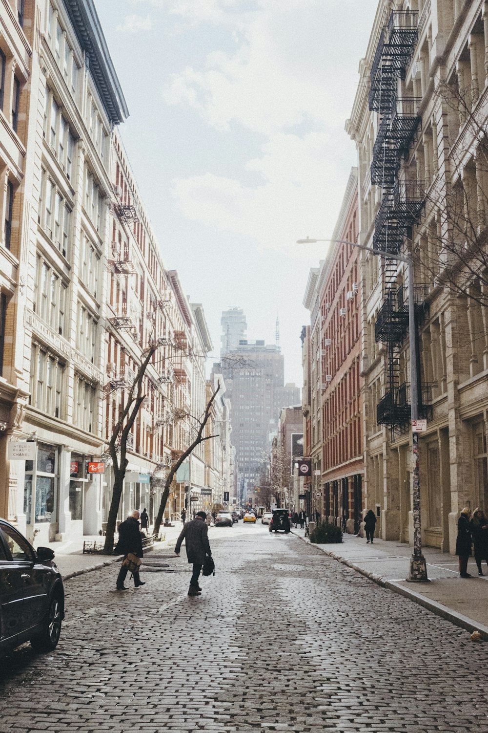 people crossing road in between buildings