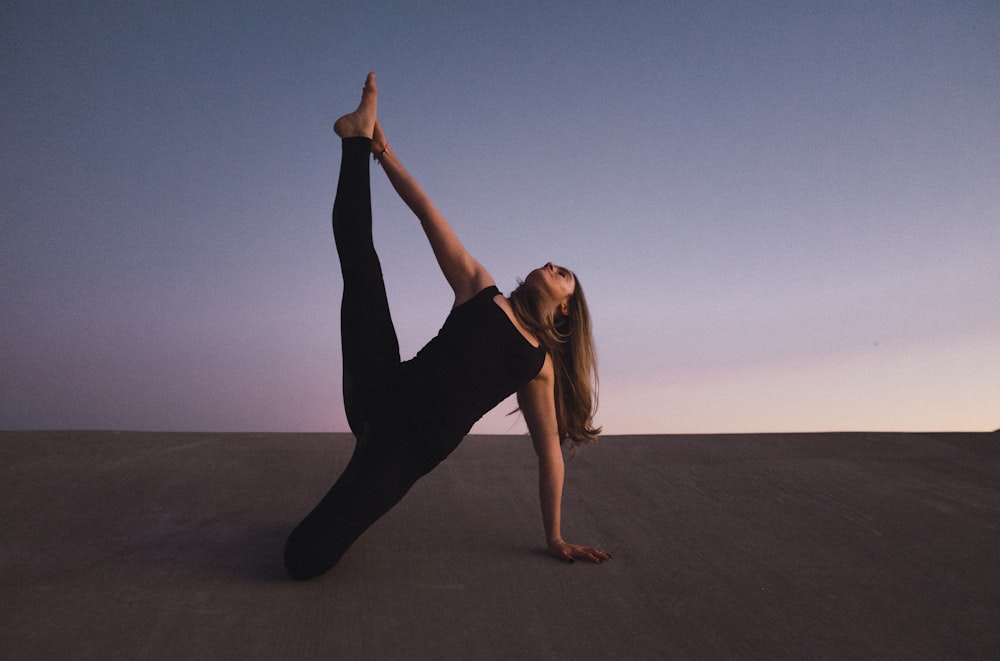 woman holding her left leg high kneeling on floor