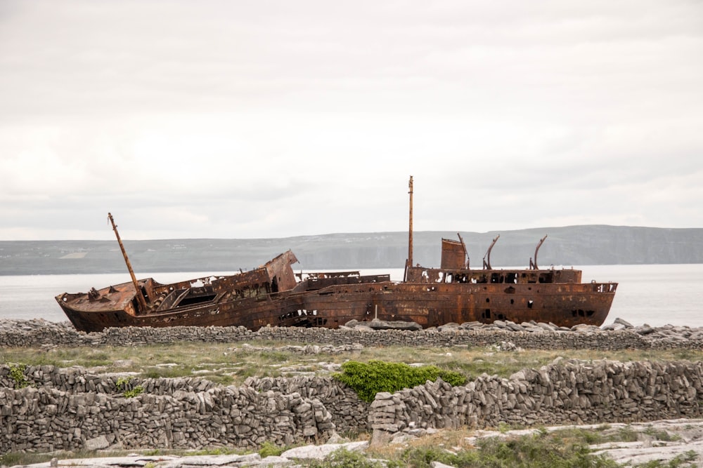 destroyed brown boat near seashore during daytime