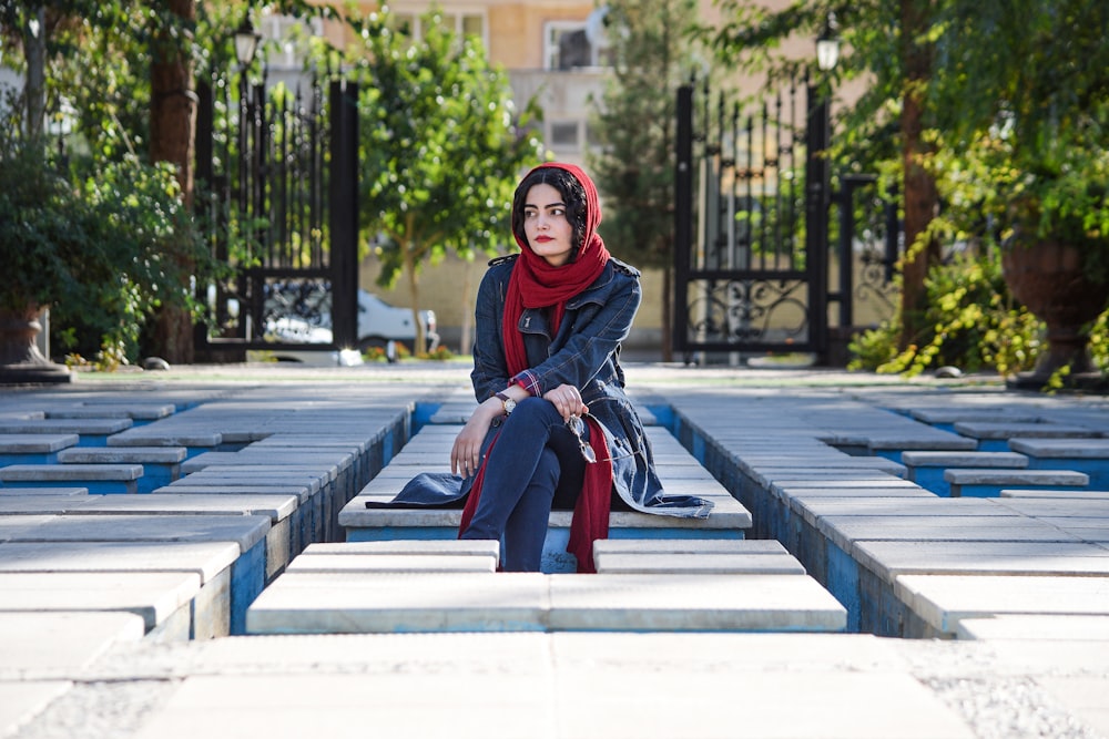 woman sitting on concrete pavement during daytime