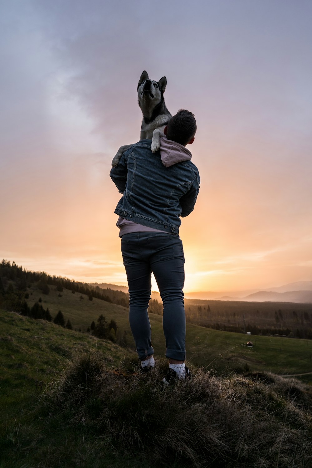 man lifting dog during sunset