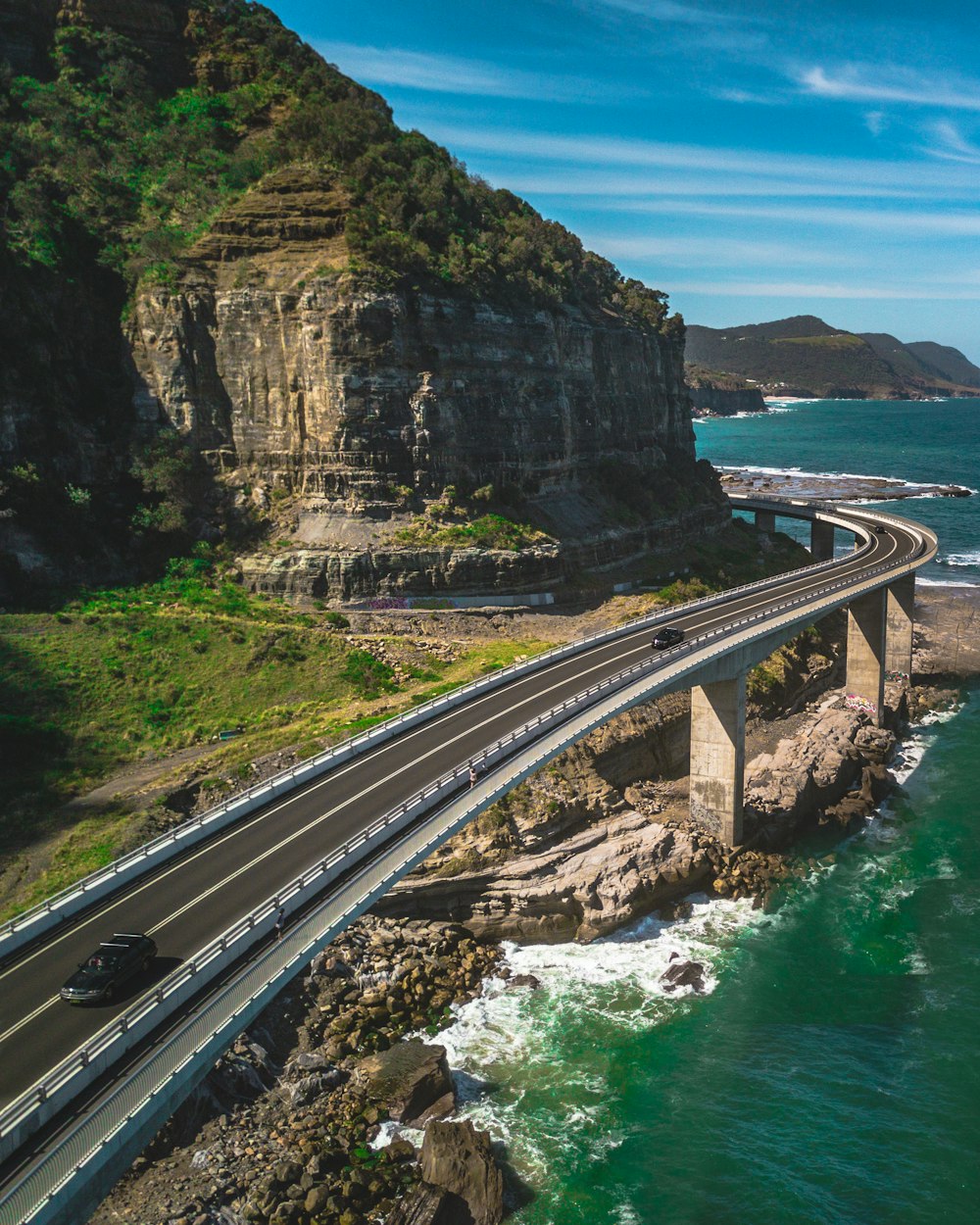 bridge road above shore near mountains during day