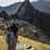 A traveler standing at the edge of Machu Picchu during sunrise, surrounded by misty mountains.