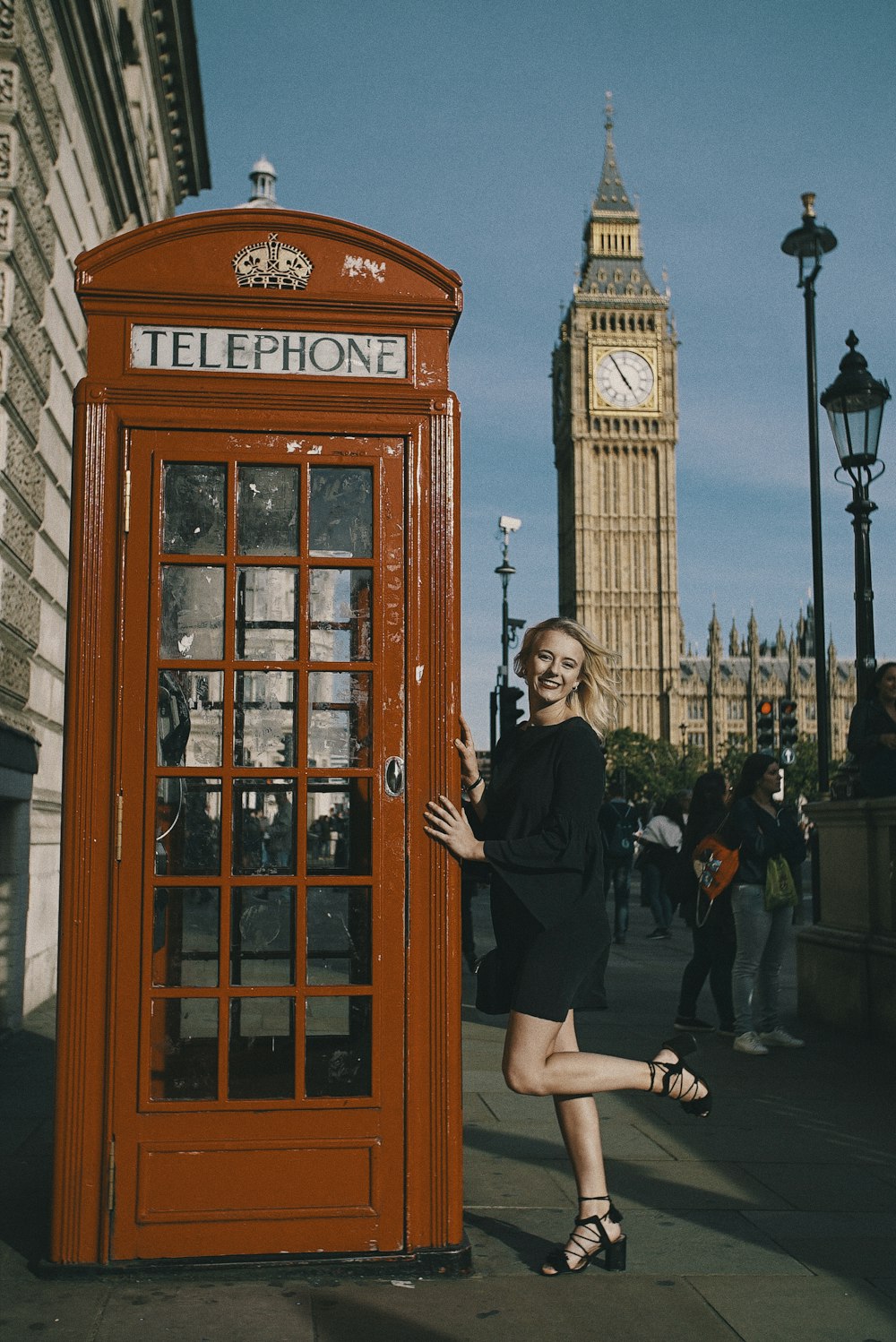 woman posing beside telephone booth with Big Ben at the back
