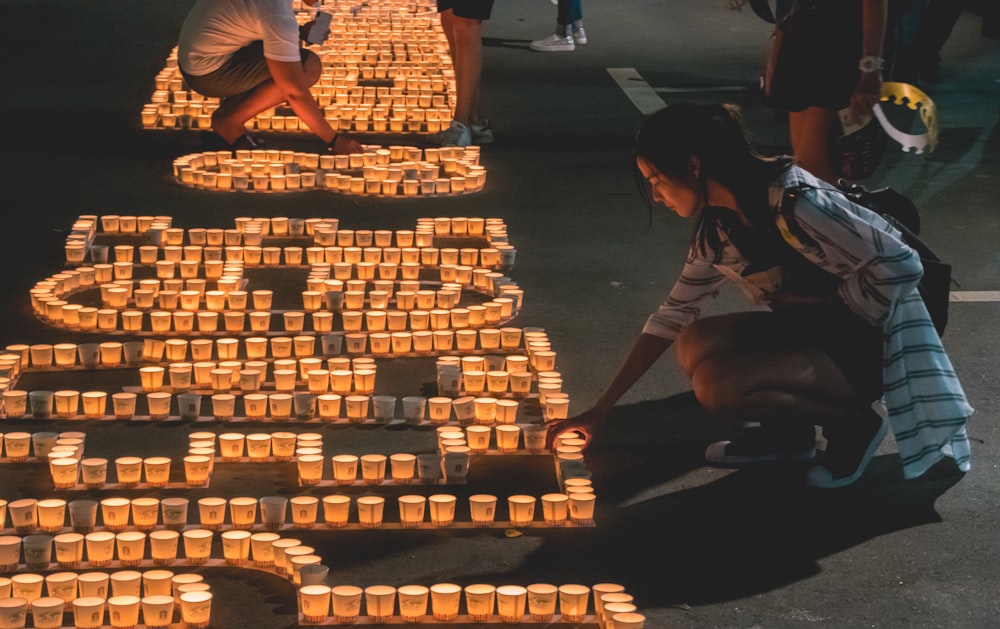 woman wearing white and gray jacket holding candle during night time