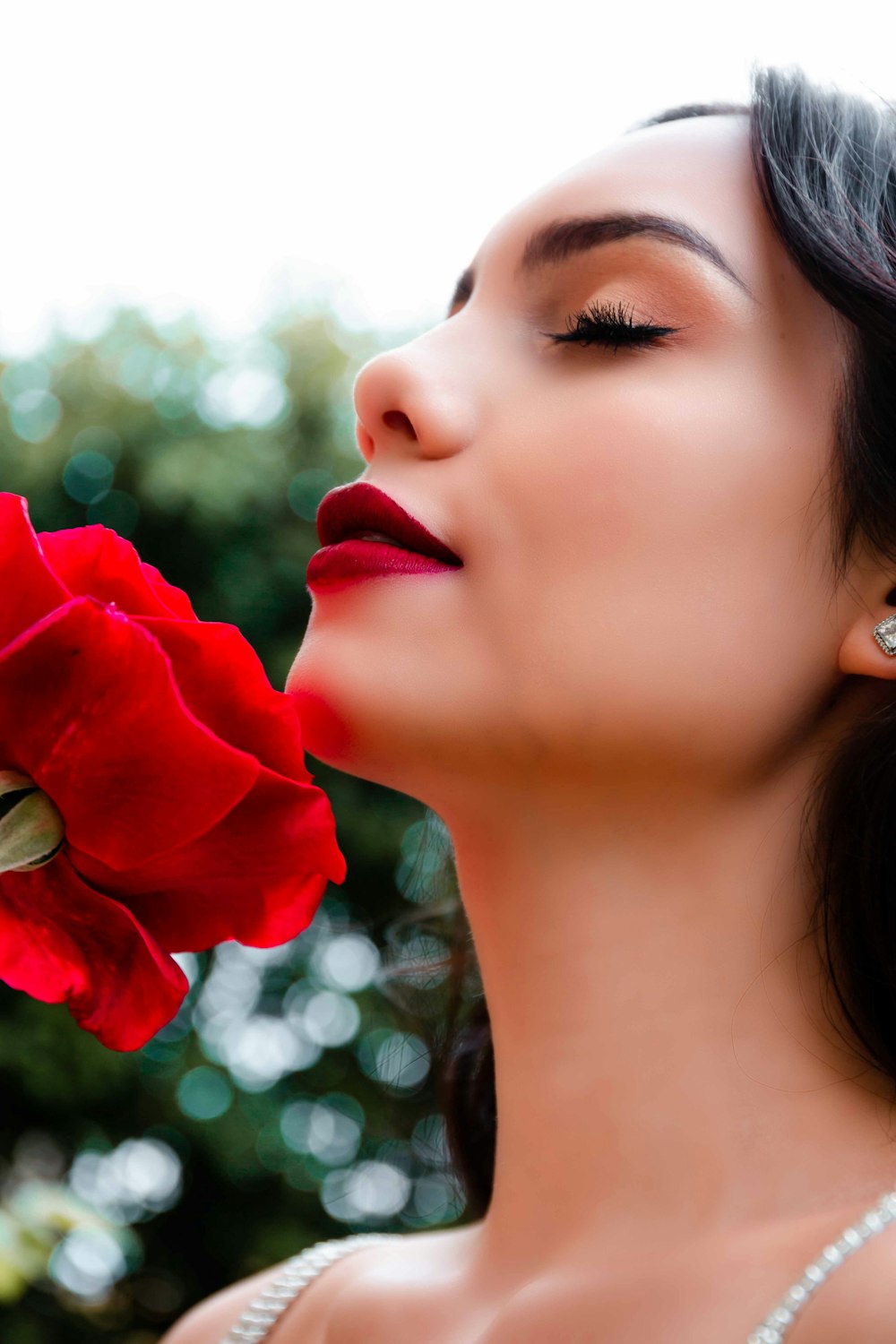 woman smelling red flower