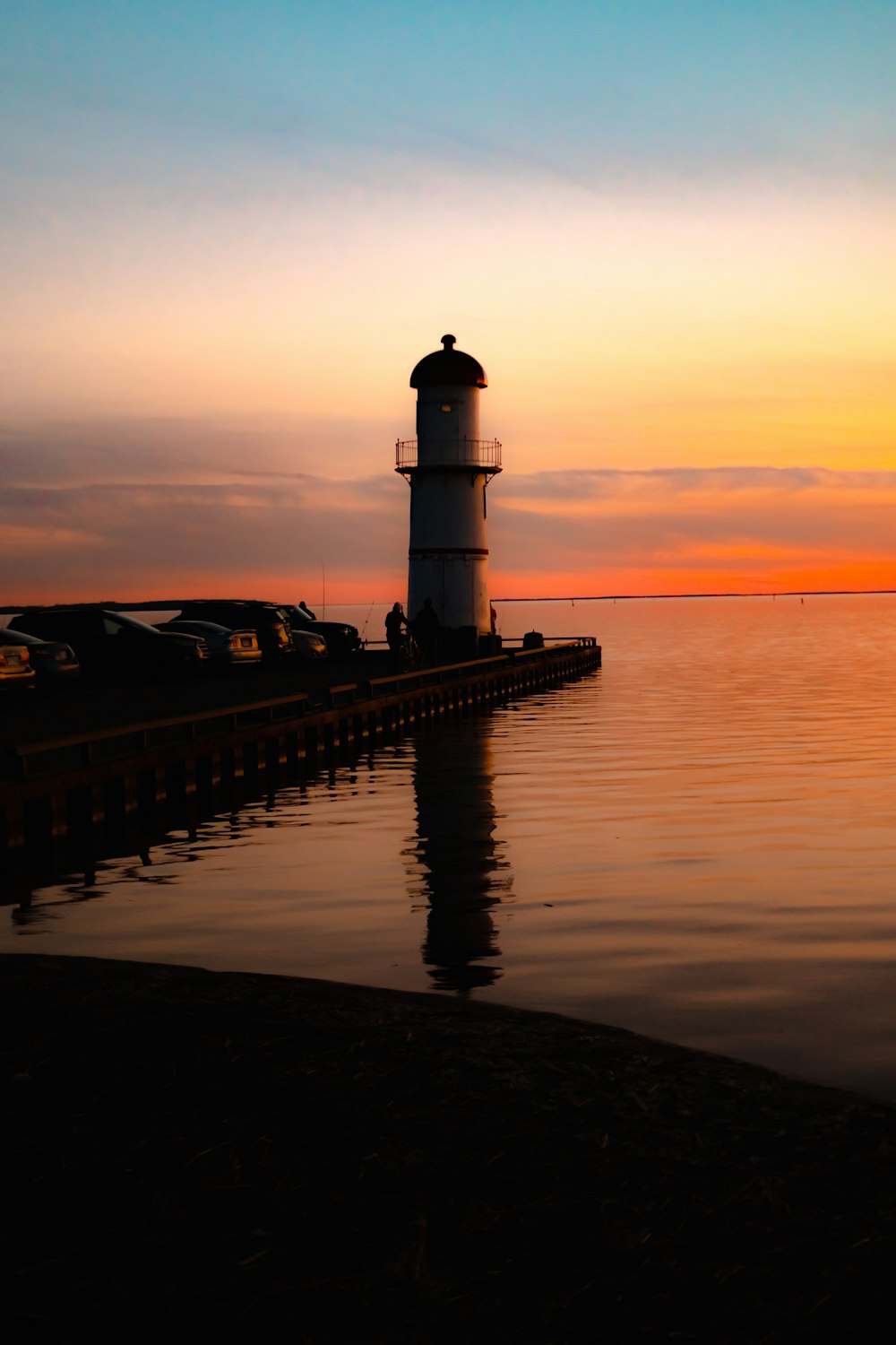 white and black lighthouse near seashore at golden hour