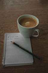A checklist on a desk with a laptop and a cup of coffee.