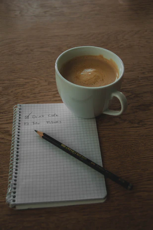 A travel checklist handwritten on a notepad next to a cup of coffee and a cruise brochure.