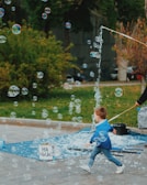 A smiling child playing with bubbles in a sun-drenched park.
