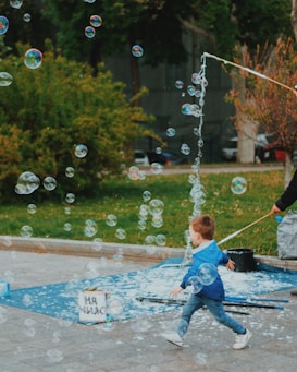 A smiling child playing with bubbles in a sun-drenched park.