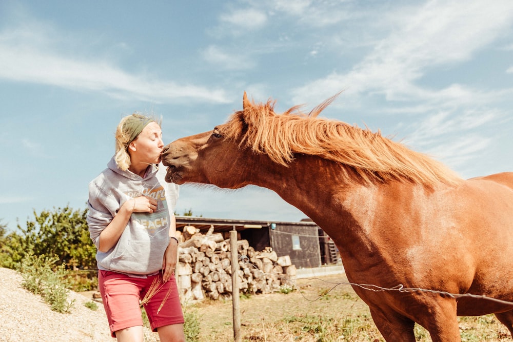 Frau küsst braunes Pferd