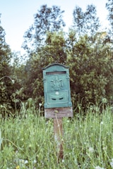 A rustic wooden mailbox post surrounded by blooming flowers and greenery.